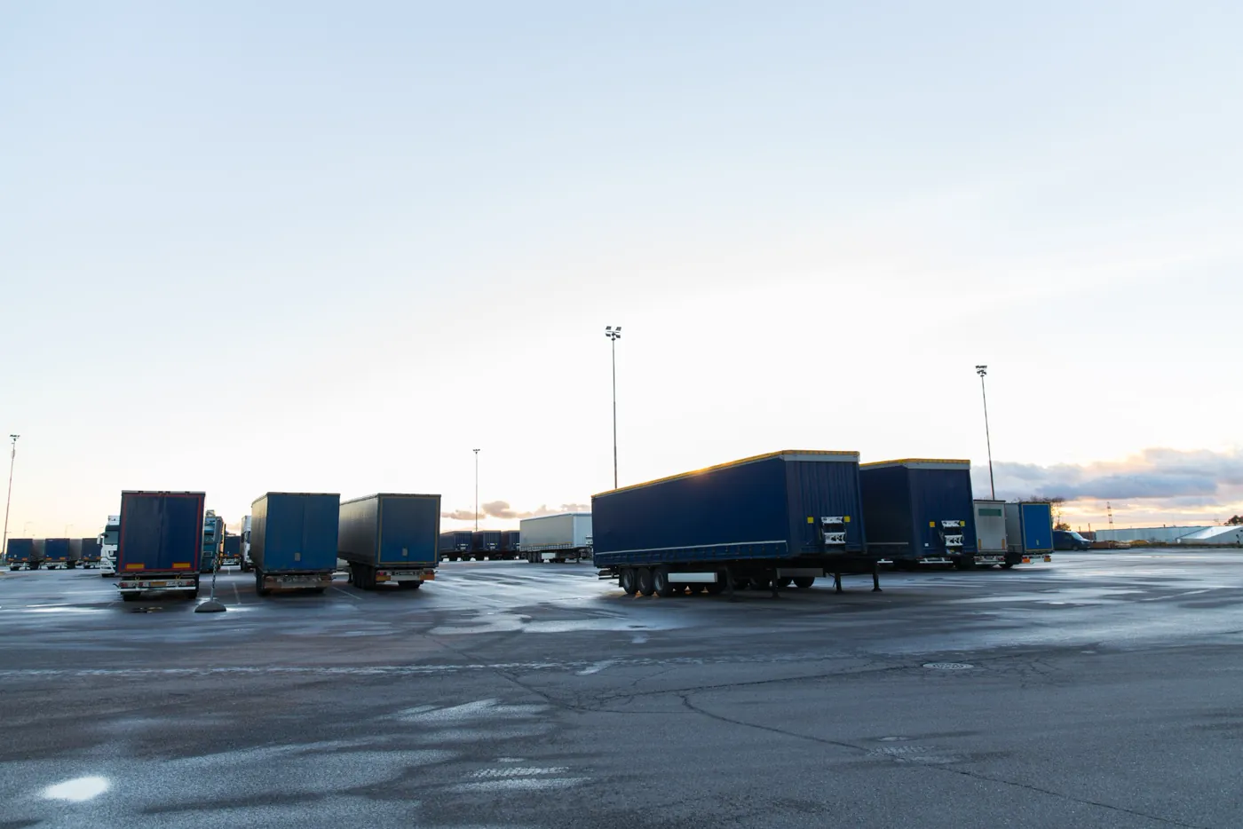 Pátio externo com carretas estacionadas diante de grandes galpões logísticos