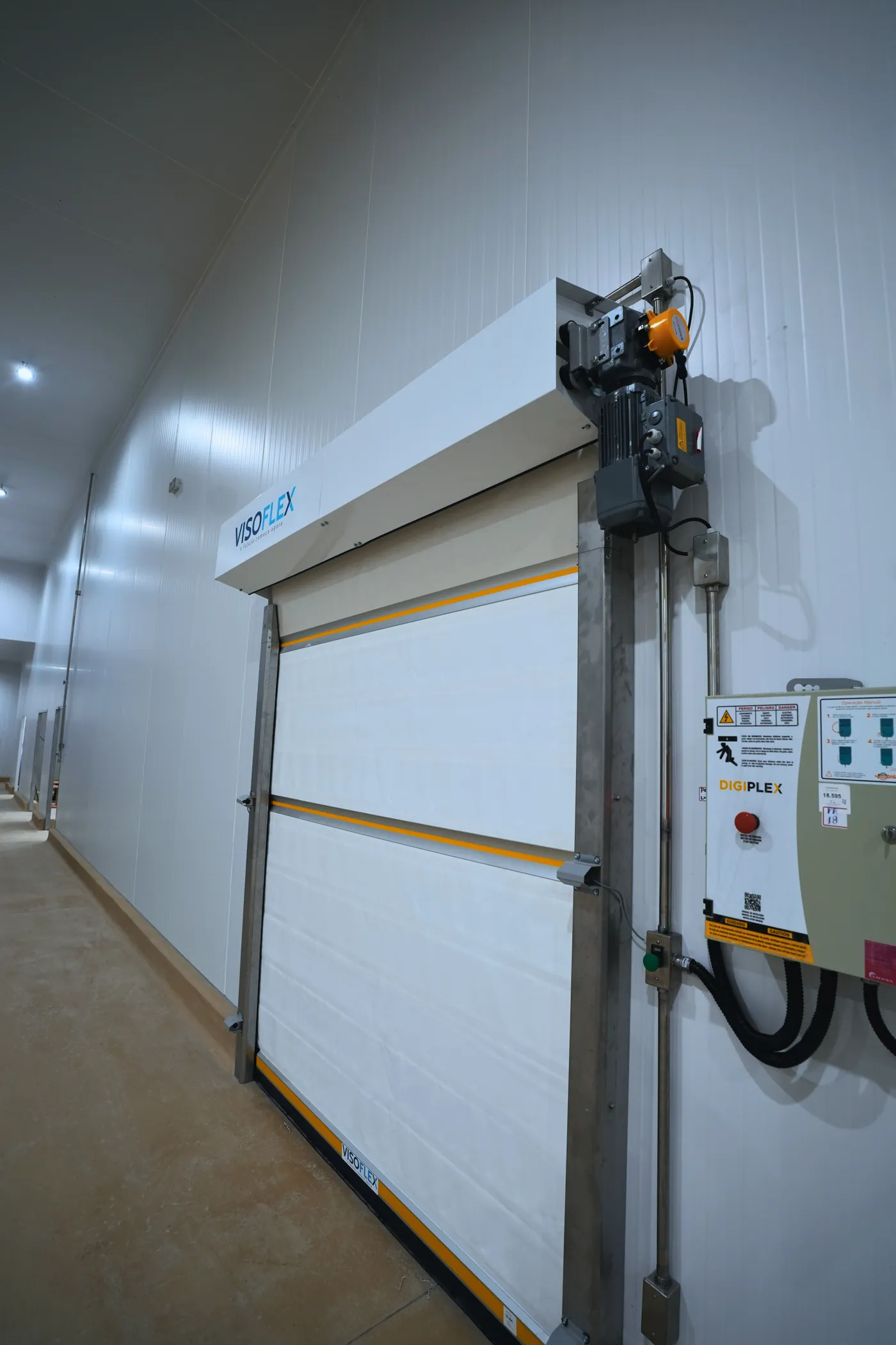 Porta rápida Visoflex VFX103 Insulada branca com quadro de comando, vista de lado em área refrigerada