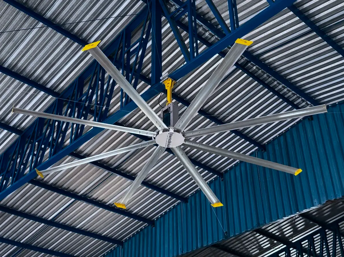 Ventilador HVLS Visoflex com pás de pontas amarelas sob telhado metálico de galpão