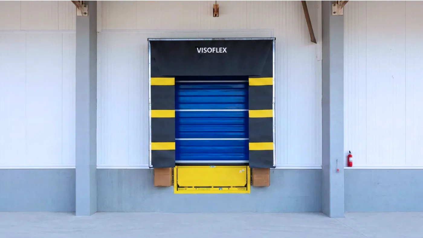 Vista frontal de porta de doca Visoflex VFX103 Dock Insulada azul com abrigo de doca e nivelador amarelo em fachada de armazém