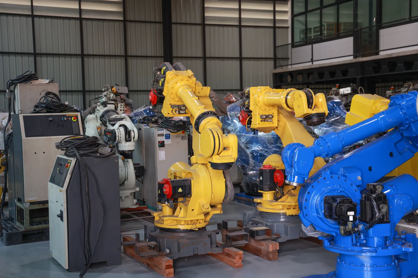 Robôs industriais amarelos e azuis enfileirados em fábrica de automação