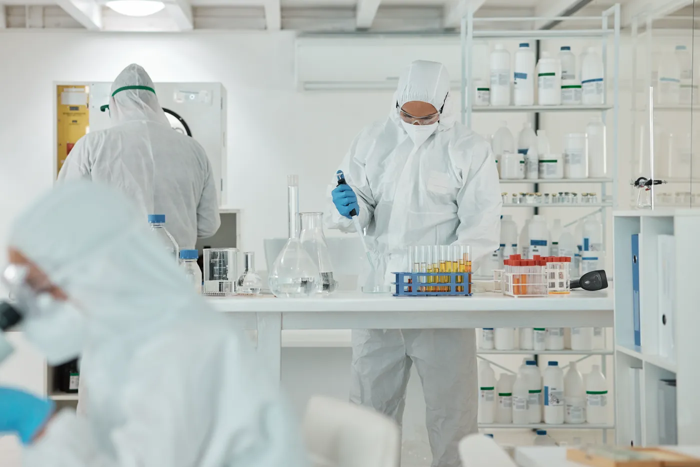 Pesquisadores paramentados realizando testes em laboratório branco