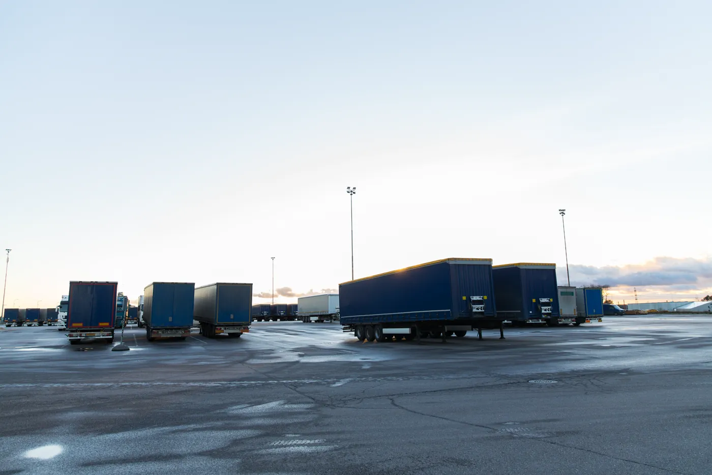 Caminhões estacionados em pátio externo de transportadora ao entardecer