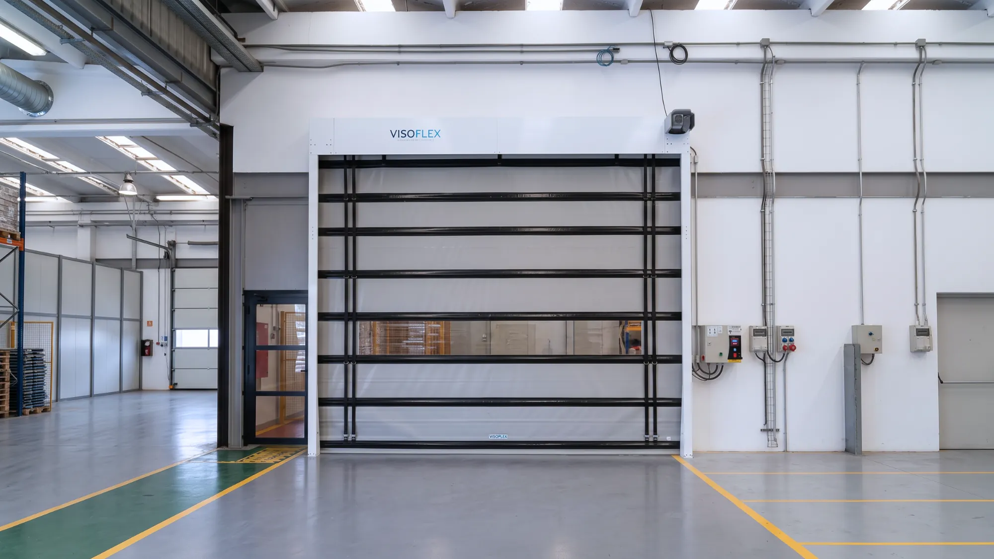 Porta rápida Visoflex VFX501 de grande vão com tecido escuro e perfis tubulares em galpão industrial