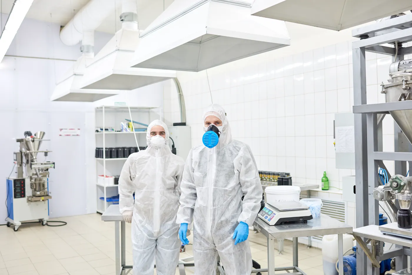 Operadores com roupa de proteção completa em área de produção farmacêutica