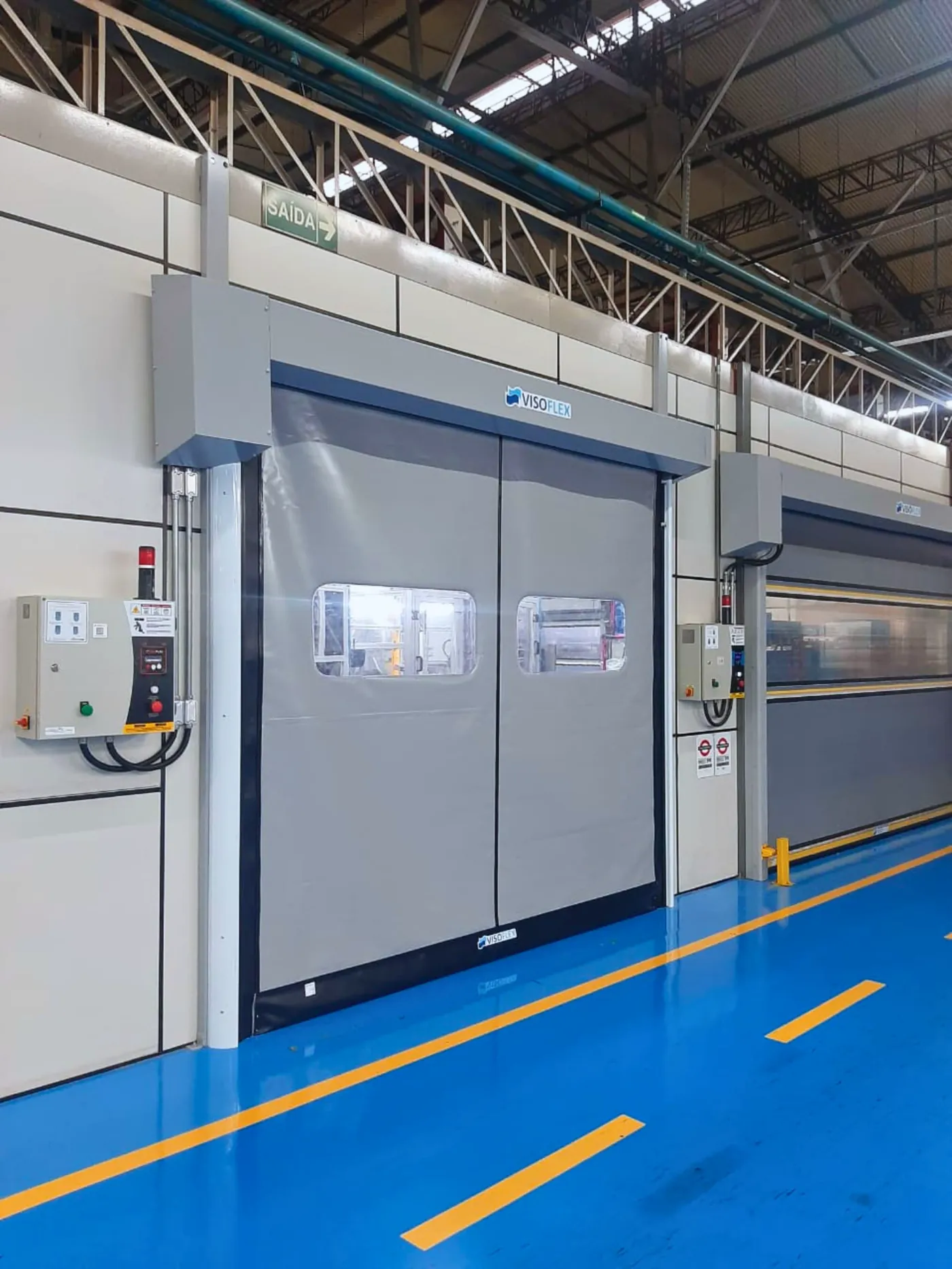 Portas rápidas VFX702 Clean cinza instaladas em corredor industrial com piso epóxi azul