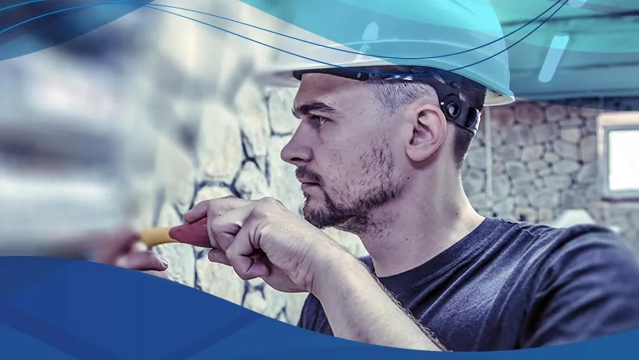 Técnico de capacete fazendo manutenção em equipamento industrial